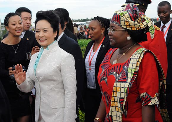 Chinese First Lady, Madame Peng Liyuan, left,, waves as she is accompanied by Tanzanian First Lady, Salma Kikwete, right, at Julius Nyerere International Airport in Dar es Salaam.