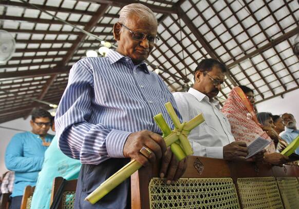 An Indian Christian devotee attends a Palm Sunday Mass with others as he hold crosses made of blessed palms at St. Paul`s Church in Bangalore.