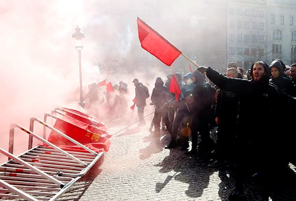 Counter demonstrators throw smoke bombs and wave red flags as they protest against a rallyby the anti Muslim organization Swedish Defense League (SDL) in central Malmo, Sweden.