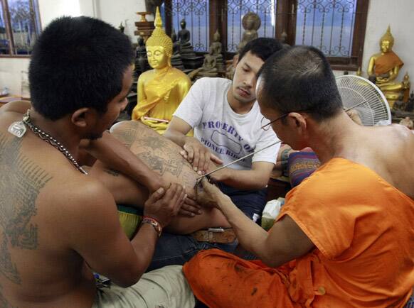 A Buddhist monk, right, uses needle to tattoo the back of a man during the `Wai Kru` or paying honest to masters ceremony at Bang Phra temple in Nakhon Pathom province just south of Bangkok.