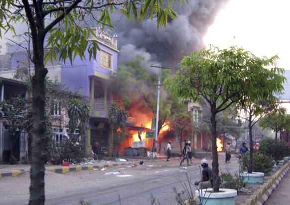 Local residents walk on a road near a burning building following ethnic unrest between Buddhists and Muslims in Meikhtila, Mandalay division, about 550 kilometers (340 miles) north of Yangon, Myanmar.
