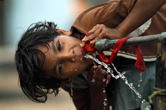 A girl drinks water from a roadside tap at a slum area, on the eve of World Water Day in Allahabad.