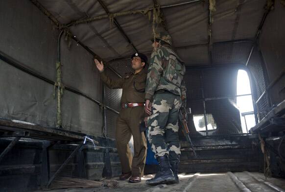 Security officers examine bullet holes inside a damaged vehicle at the site of a shootout on the outskirts of Srinagar.