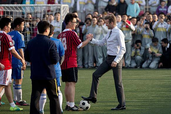 David Beckham, in his suit, shakes hands with students of Beijing`s No. 2 High School after he played soccer with them during an event to promote the sport in China.