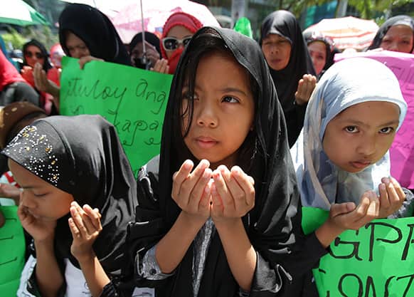 Filipino Muslim children pray during a rally outside the Office of the Presidential Adviser on the Peace Process in suburban Pasig, east of Manila, as they expresses concern for the alleged slow progress of a peace process between the government and a Muslim rebel group.