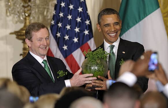 President Barack Obama and Irish Prime Minister Enda Kenny hold up a bowl of Irish shamrocks during a St. Patrick`s Day reception in the East Room of the White House in Washington.
