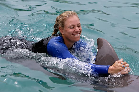 Tennis player Angelique Kerber, of Germany, swims with a dolphin during a photo opportunity, at Miami Seaquarium in Key Biscayne, Fla.