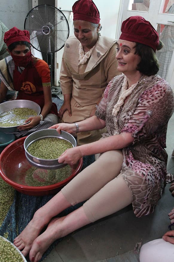 Cherie Blair, center, wife of former British Prime Minister Tony Blair tries her hand at cleaning pulses during her visit to the Rural Distribution Network India (RUDI) center in Surendranagar district, Gujarat.