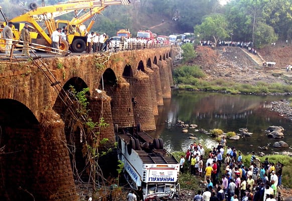Rescuers and others gather at the site of a bus accident in Ratnagiri district, Maharashtra. The bus packed with passengers crashed through a guard rail and fell off a bridge, killing at least 37 people and injuring another 15, police said..