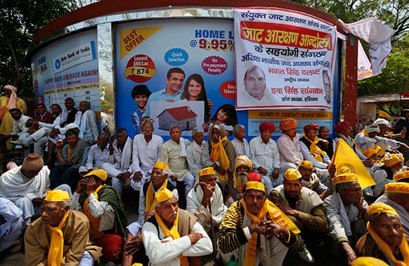 People from the northern Indian community of mainly farmers and herders called `Jat`, sit near a poster promising cheap home loans as they stage a protest near the Indian Parliament in New Delhi.