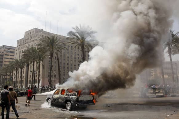 Egyptians extinguish a burning police vehicle, which has been set afire by angry protesters in Tahrir Square, once the epicenter of protests against former President Mubarak, in Cairo.