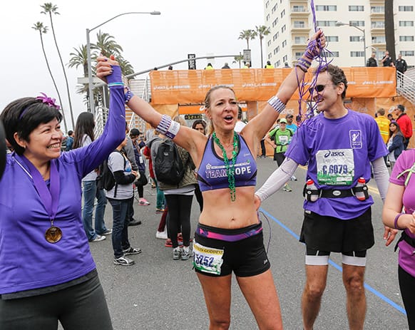 Julie Weiss, 42, center, with her fiancee David Levine, right, and six month pancreatic cancer survivor Lupe Romero, left, celebrate after Weiss completed her 52 marathons in 52 weeks, in dedication to her father who died from pancreatic cancer at age 75, in Santa Monica, Calif.