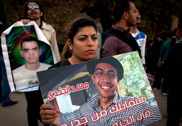Two Egyptian protesters carry posters with pictures of slain activists during an anti-Muslim Brotherhood protest in front of the Brotherhood`s headquarters, in Cairo, Egypt.