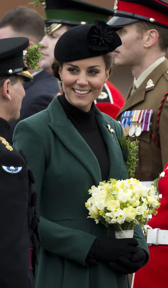 Britain`s Kate the Duchess of Cambridge holds flowers after presenting traditional sprigs of shamrocks to members of the 1st Battalion Irish Guards at the St Patrick’s Day Parade at Mons Barracks in Aldershot, England.
