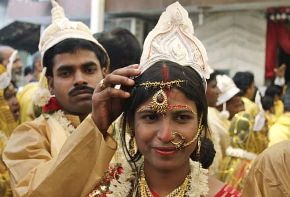 A groom adjusts the headgear of his newly married bride during a mass community marriage in Kolkata.