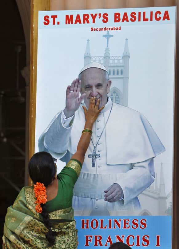 An Indian Catholic devotee touches a portrait of Pope Francis put up at the entrance of Saint Mary`s Basilica in Hyderabad.