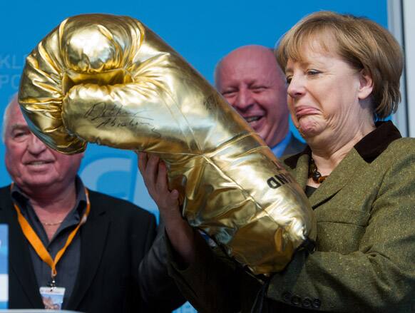 German Chancellor Angela Merkel grimaces as she holds a giant golden boxing glove during the representatives meeting of the Christian Democratic Party, CDU, in the state of Mecklenburg-Western Pomerania in Grimmen, northern Germany.