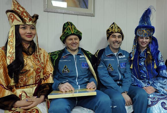 Russian cosmonauts Oleg Novitsky and Yevgeny Tarelkin, wearing Kazakh traditional costumes, pose for a photo with Kazakh women after their return to the earth with NASA`s astronaut Kevin Ford in a Soyuz space capsule at an airport of Kostanai, Kazakhstan.