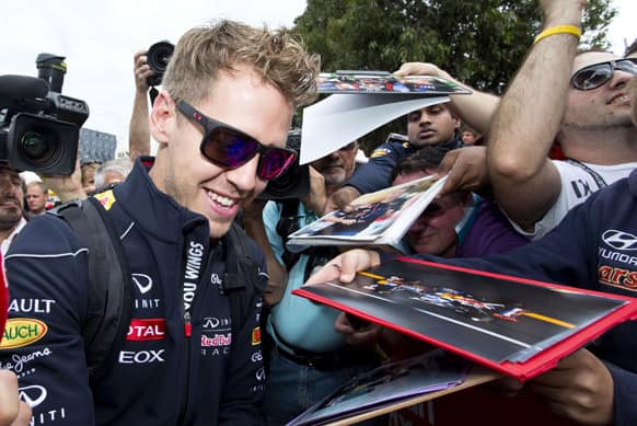 Red Bull driver Sebastian Vettel of Germany signs his autographs for fans after arriving at Albert Park Track ahead of the official qualifying for Sunday`s Australian Formula One Grand Prix in Melbourne, Australia.