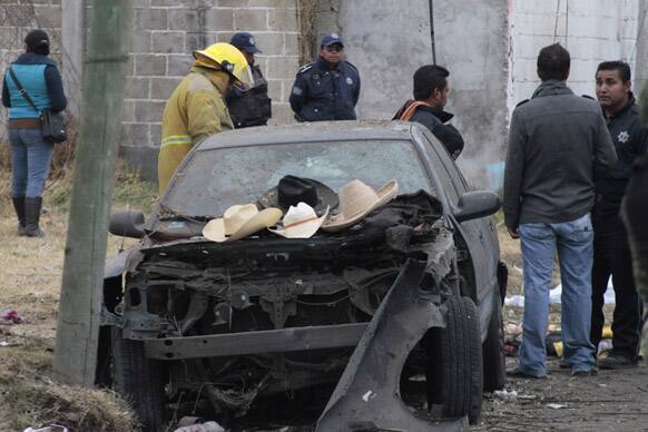 Hats belonging to victims sit on the hood of a damaged car as emergency workers gather a the scene where a truck loaded with fireworks exploded during a religious procession in the town of Nativitas, Mexico.