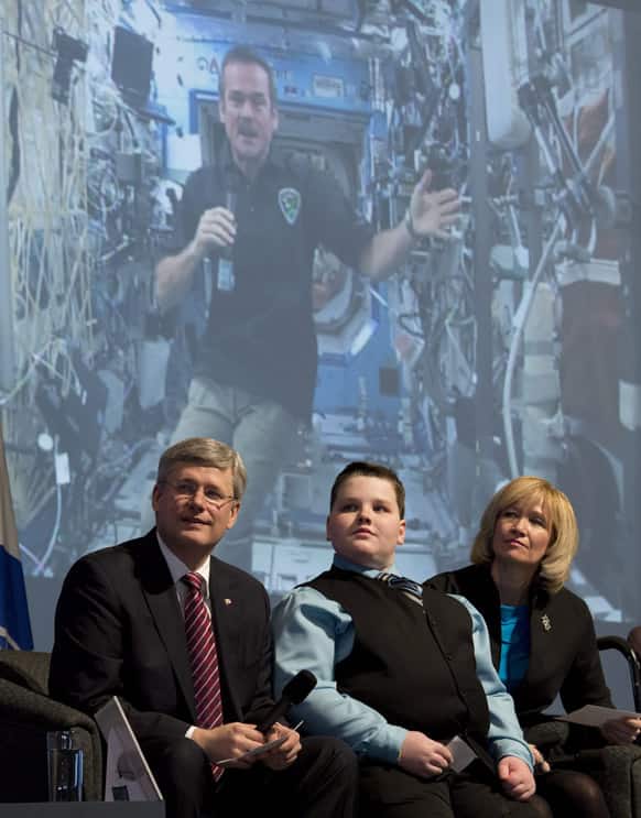 Darcy McRae sits with Canadian Prime Minister Stephen Harper, left, and his wife Laureen Harper as he asks Commander of the International Space Station Chris Hadfield a question via video conference, in Ottawa.