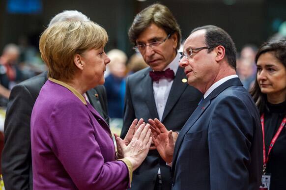 German Chancellor Angela Merkel speaks with French President Francois Hollande during a round table meeting at an EU summit in Brussels.