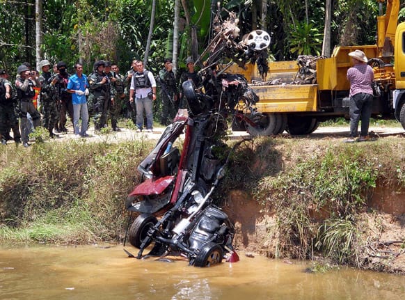 The wreckage of a pickup truck, which had been carrying Thai police officers, is lifted off a canal after hitting a bomb set by suspected insurgents in Rue So district of Narathiwat province, southern Thailand.