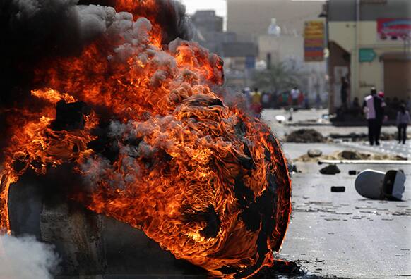 An old water storage tank burns as Bahraini anti-government protesters look out for riot police in Malkiya village, Bahrain.