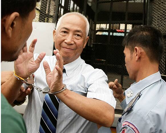 Local radio station owner Mam Sonando, center, is escorted by court security personnel as he enters an appeals court in Phnom Penh, Cambodia.