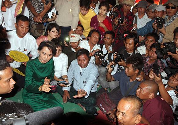 Myanmar opposition leader Aung San Suu Kyi talks to a protester as she pays her respects to Buddhist monks in Tone village, an area near the Letpadaung copper mine project, in Monywa, 760 kilometers (450 miles) north of Yangon, central Myanmar.