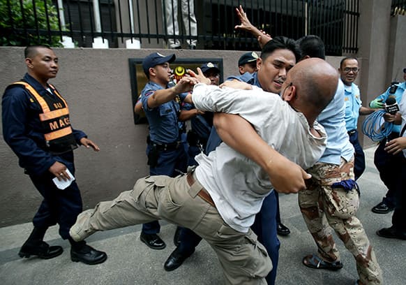 A Filipino policeman prevents activists from touching a sign of the Malaysian Embassy during a rally to call for peace in Sabah at the financial district of Makati, south of Manila, Philippines.