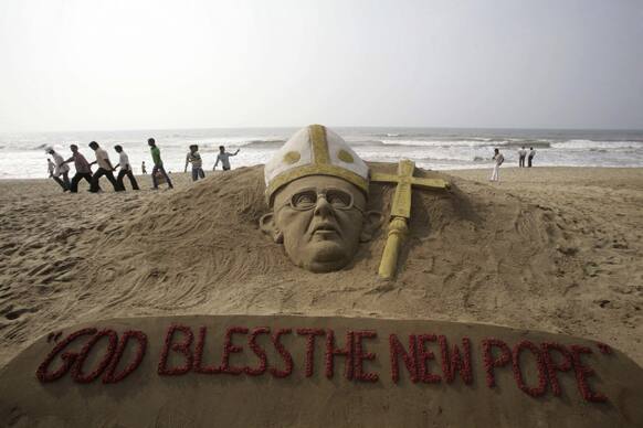 People walk past a sand sculpture of the new pope at the Golden Sea beach on the Bay of Bengal coast in Puri, Orissa state, India.