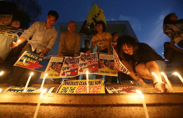 Filipino activists light candles as they hold signs calling for peace in Sabah, Borneo during a rally at the University of the Philippines, Quezon city, north of Manila, Philippines.