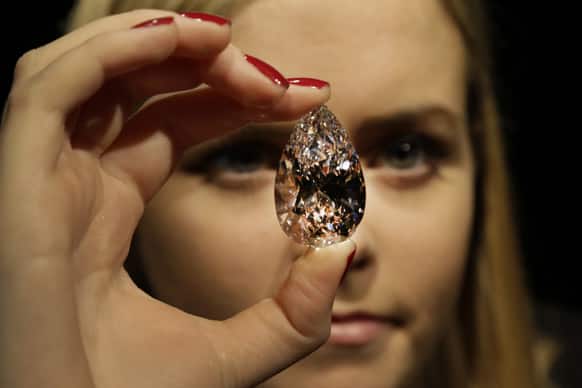 An auction house employee holds a pear-shaped diamond weighing 101.73 carats, as she poses for the photographers in central London.