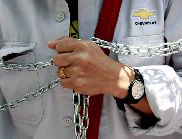 A worker from General Motors Thailand, who makes Chevrolet cars, wraps a chain around herself during a rally outside the US Embassy in Bangkok. About 200 workers took part in the rally demanding the embassy to put pressure on their employer to provide better working conditions and fair employment.
