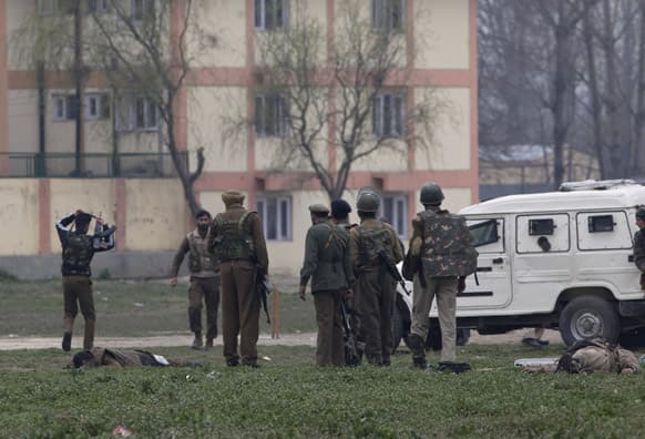 Police and paramilitary soldiers stand near the bodies of their colleagues after a gun battle in Srinagar.