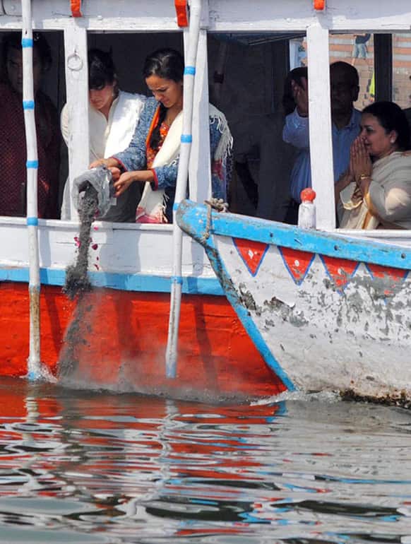 Anoushka Shankar, center, and Norah Jones daughters of sitar maestro Pandit Ravi Shankar immerse his ashes in the Ganges River, as his wife Sukanya, right, reacts in Varanasi.