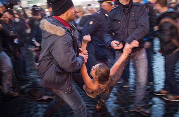 An Femen group activist is detained by police officers following a protest against the pope outside St. Peter`s Square as cardinals took an oath in the Sistine Chapel at the start the conclave to elect a new pope at the Vatican.
