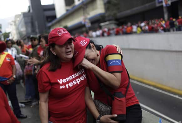 Supporters of late President Hugo Chavez embrace as they listen to a recording of Chavez singing the national anthem at the end of a political rally in support of acting President Nicolas Maduro running for president in upcoming elections in Caracas, Venezuela.