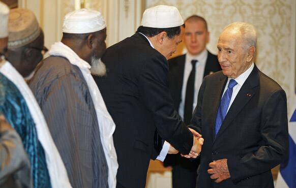 Israeli President Shimon Peres is greeted by the President of the Conference of the Imams of France Hassan Chalghoumi at the start of a meeting with Imams, in Paris.