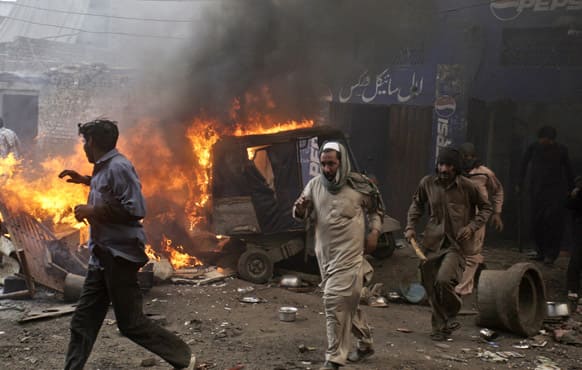 Pakistani men, part of an angry mob, run after burning belongings of Christian families, in Lahore.