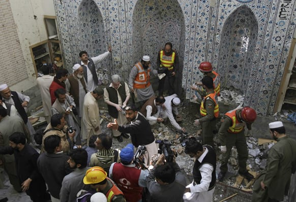 Pakistani security officials and rescue workers examine the site of bomb blast inside a mosque in Peshawar.