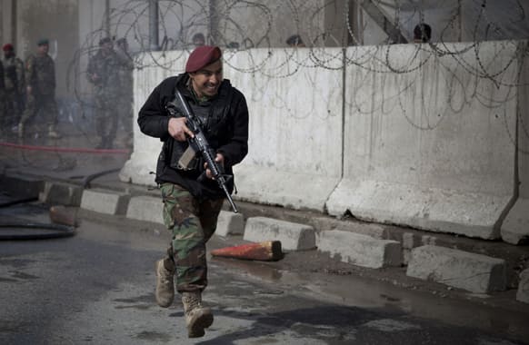 An Afghan Army soldier runs outside the Afghan Defense Ministry after a suicide bomber on a bicycle struck outside the ministry, killing at least nine Afghan civilians as US Defense Secretary Chuck Hagel visited Kabul, Afghanistan.