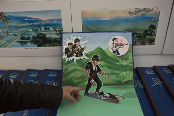 A North Korean teacher holds open a children`s pop-up book, which depicts a U.S. soldier killing a Korean woman with a hatchet, in a library room at Kaeson Kindergarten in central Pyongyang.