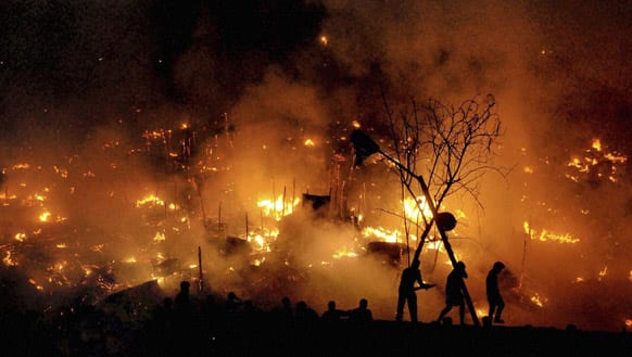 People are silhouetted as a fire engulfs a shanty town in the eastern Indian city of Bhubaneswar. About 300 homes were gutted in the fire, according to reports.