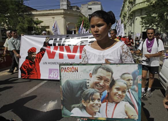 A young woman holds a poster of Venezuela`s late President Hugo Chavez during a march to pay him tribute in Asuncion, Paraguay.