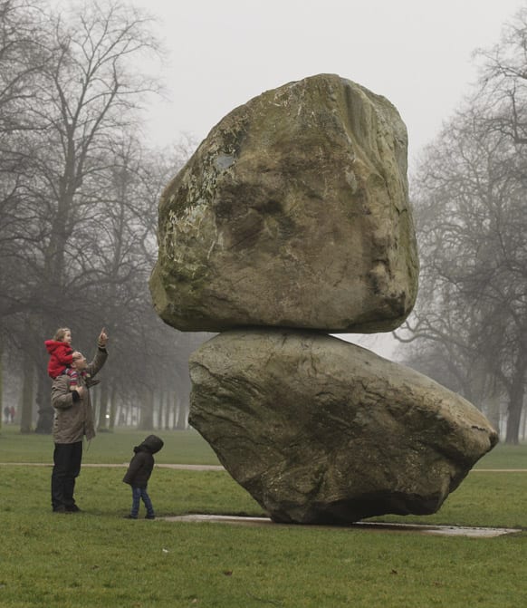 Visitors take a close look at the large-scale boulder sculpture entitled `Rock on Top of Another Rock`, by the artistic duo Fischli/Weiss during its unveiling at the Serpentine Gallery in Hyde Park, London.