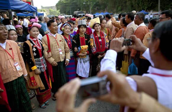 Representatives of Aung San Suu Kyi’s National League for Democracy party, bearing ID cards, pose for photographs with women dressed in ethnic attire outside the venue of first ever NLD party congress in Yangon.