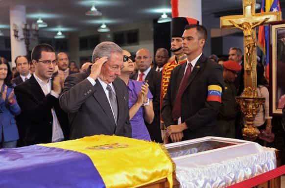Cuba`s President Raul Castro salutes as he stands next to the coffin containing the body of Venezuela`s late President Hugo Chavez during his wake at a military academy where his body will lie in state until his funeral in in state in Caracas, Venezuela.