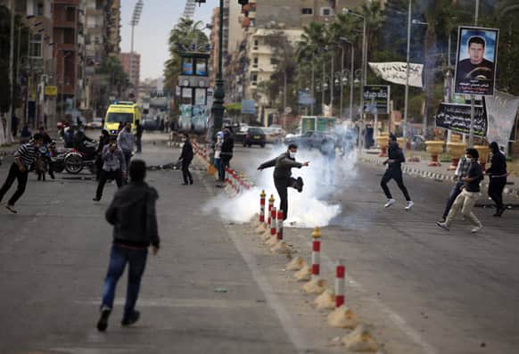 An Egyptian protester kicks a tear gas canister fired by riot police, not pictured, during clashes near a state security building in Port Said, Egypt.